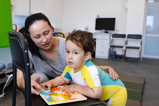 Physical therapist motivates a boy to do difficult rehabilitation exercises with a reward in the form of interesting toys. Children's rehabilitation