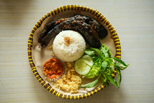 Authentic Indonesian Grilled Fish Meal with Rice, Sambal, and Fresh Vegetables. Traditional Asian Cuisine Dish.