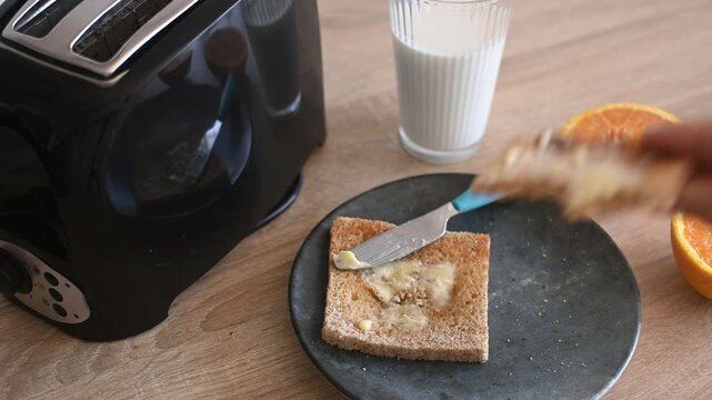 Hand picking up buttered toast from a breakfast plate