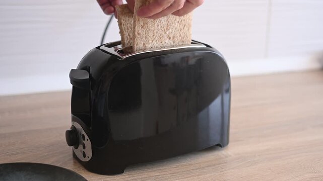 Placing bread slices into a toaster to make breakfast toast