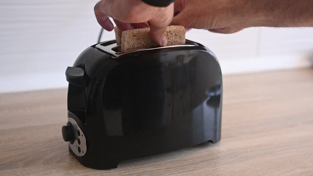 Placing bread slices into a toaster to make breakfast toast