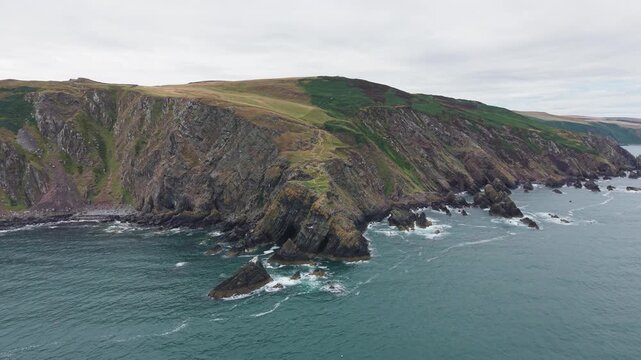 High-angle view on the dramatic, steep rocky cliffs and rugged coastal headland at Fast Castle Head, showcasing the geological formations and North Sea in Berwickshire, Scotland.