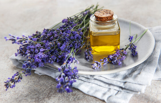 Lavender essential oil bottle with fresh purple flowers
