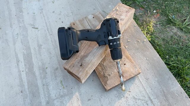 Cordless electric drill on a wooden board, showcasing do-it-yourself carpentry work with professional power tools on a construction site