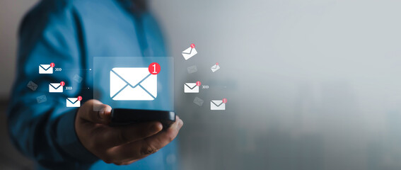 Naklejka na ściany i meble Business professional holding a smartphone with email notification icons, representing digital communication, inbox management, mobile messaging, online marketing, customer support, modern business