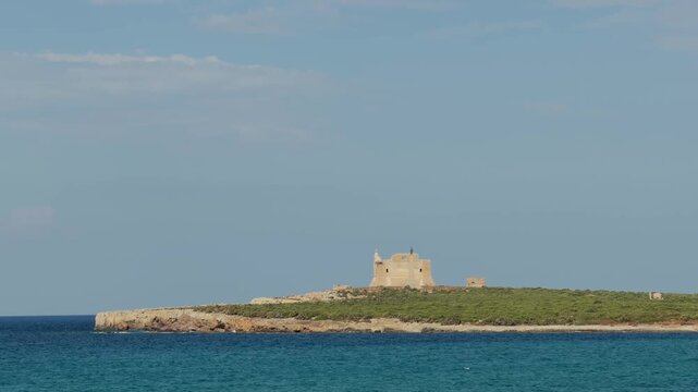 Long landscape view of Isola di Capo Passero with historic ruins and Mediterranean coastline in Sicily.