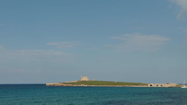 Wide angle of a White catamaran in the Mediterranean Sea near the ruins of Isola di Capo Passero in Sicily.