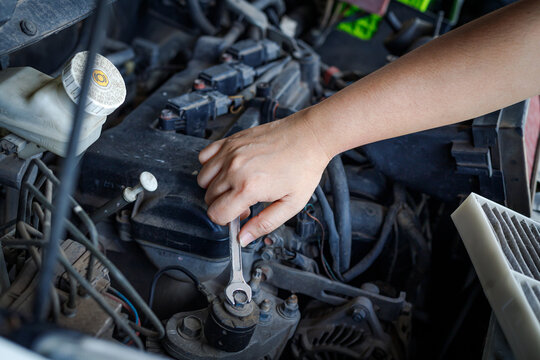 Hand of mechanic using a silver combination wrench to work on a pulley bolt