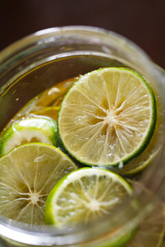 Glass jar filled with fresh lime slices preserved in honey, creating a homemade honey lime infusion. Natural ingredients for refreshing drinks, wellness, and traditional food preservation