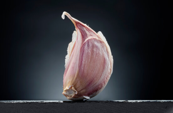 Single Garlic Clove with Skin on Dark Background
