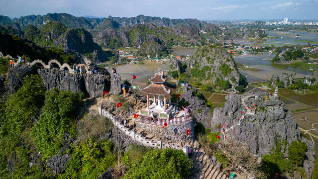 Aerial view of Hang Mua Viewpoint overlooking the limestone karst landscape of Ninh Binh, Vietnam. Scenic panorama with rice fields, mountain peaks and traditional architecture.