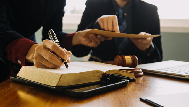 Lawyers Reviewing Legal Documents and Taking Notes During Client Consultation in Modern Law Office
