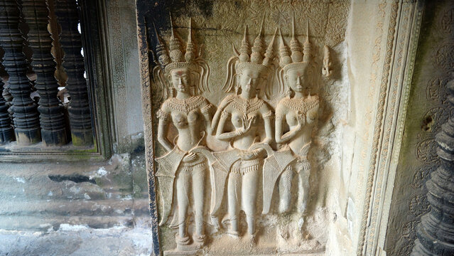 Ancient stone relief carving with Apsara dancers on a historic temple wall