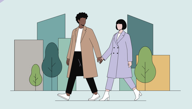 Fashionable young couple holding hands and walking together down a city street with modern buildings.