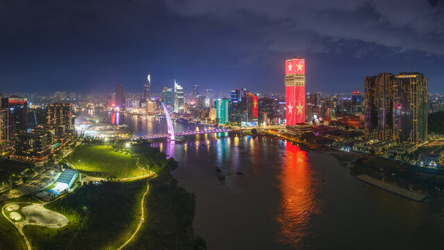 HO CHI MINH CITY, VIETNAM: Aerial view of Ba Son bridge and city center skyline illuminated with red national flag LED light at night