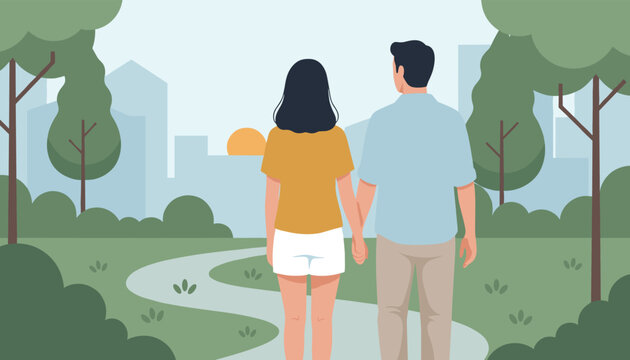Back view of a happy couple holding hands and walking together on a path in a beautiful green city park.