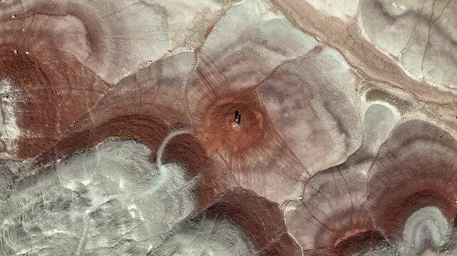 Top down drone rises above couple standing on Bentonite Hills Utah