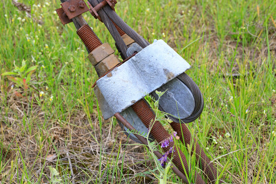 Guy-wire anchor system for securely anchoring a power line pole. Heavy steel cables and a rusty tensioning mechanism with a turnbuckle are anchored to the ground