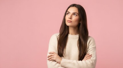 Obraz premium Thoughtful young woman with crossed arms looking up against a pink background.