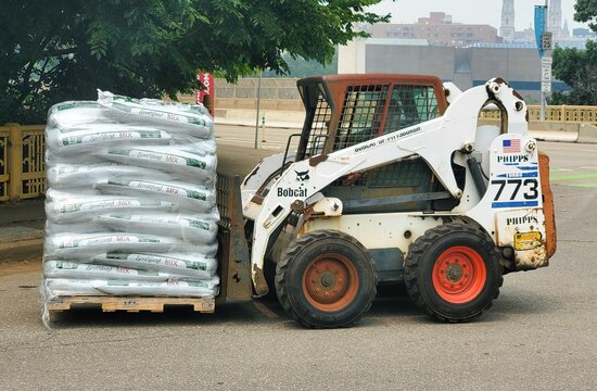 Pittsburgh, Pennsylvania, U.S.A - Jul 18, 2026 - Bobcat skid-steer lifting pallet of Southland Mix bags on the street