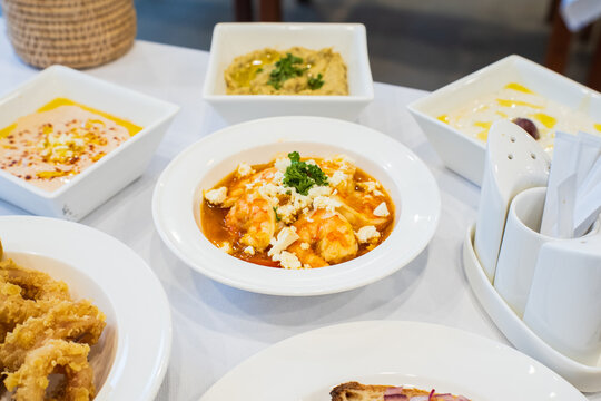 Garides saganaki, Greek Garides saganaki, shrimp saganaki with assorted Greek dishes on a table