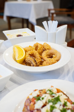 Fried calamari, Greek kalamari, Greek deep fried kalamari with lemon with assorted Greek dishes on a table