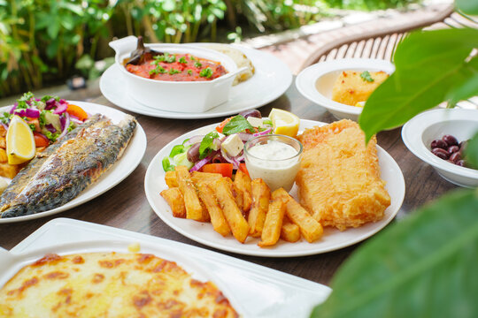 Fried fish and Greek salad, Greek deep fried dory fish, French fries and Greek salad with tartar sauce on a table