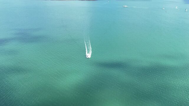 Cinematic drone footage following a motorboat across calm waters toward Gorriti Island in Punta del Este, Uruguay, on a sunny day.