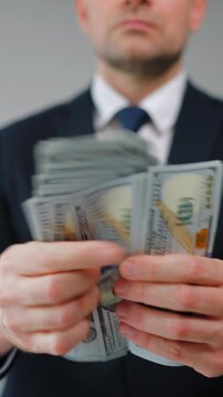 Formally dressed man is counting US Dollar bills quickly, close-up.