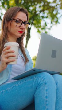 Woman sitting in the park with laptop after work day in the office. Slow motion
