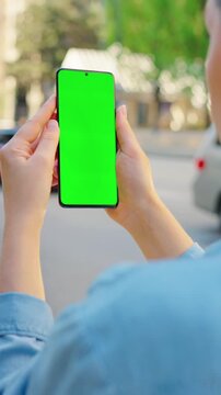 Woman is standing on the street and using smartphone with green screen