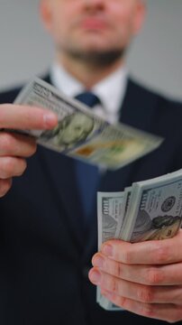 Formally dressed man is counting US Dollar bills quickly, close-up.