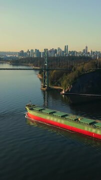 A dry cargo ship passes under the Lions Gate Bridge at dawn. Vancouver, Canada