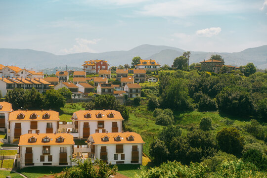 Traditional modern Basque village with white houses and orange tile roofs nestled on green hills in countryside near Bilbao, Basque Country, Northern Spain.
