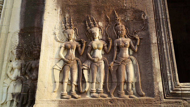 Sacred Hindu Devata goddess sculptures on a weathered sandstone wall at sunset