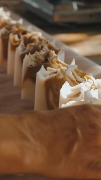 hand reaches toward handcrafted soap bars on rustic tabletop, warm light highlighting calm spa display