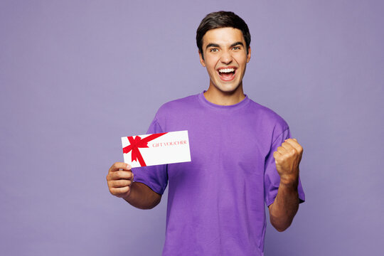 Young man he wear violet t-shirt casual clothes hold gift certificate coupon voucher card for store do inner gesture isolated on plain pastel light purple background studio portrait Lifestyle concept
