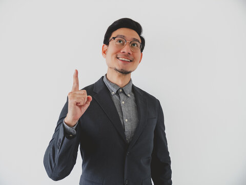Young Asian man in business attire pointing finger up, looking inspired with a new idea.
