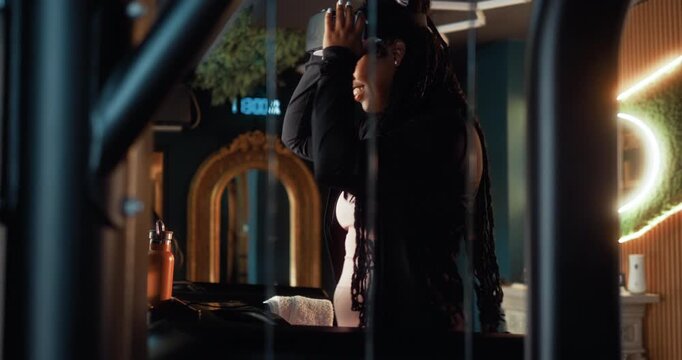 Excited Black woman selects a virtual route and uses a VR headset on a treadmill in a smart gym, enjoying an immersive cardio workout with modern fitness technology.