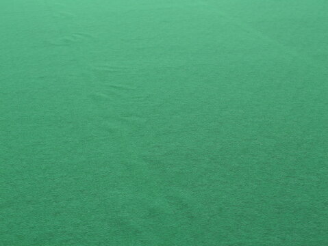 Close-up of a smooth green felt fabric texture with a soft matte finish and subtle folds, creating an abstract and minimal background.