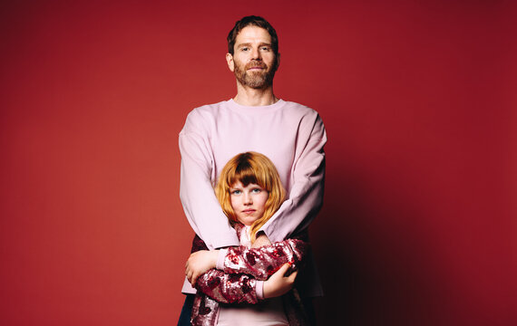 Standing together, father and daughter express family love and protection in the studio