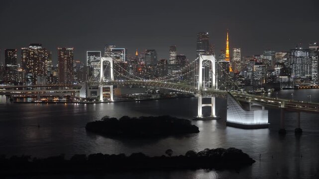 Locked off shot showing the Rainbow Bridge and Tokyo skyline at night from Odaiba, Tokyo, Japan. 