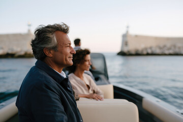 Fototapeta premium A contemplative man on a boat enjoys the soothing experience of cruising through calm waters, reflecting on life and embracing the peaceful atmosphere surrounding him.