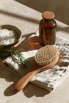 Dry body brush with oil bottle and salt on stone surface