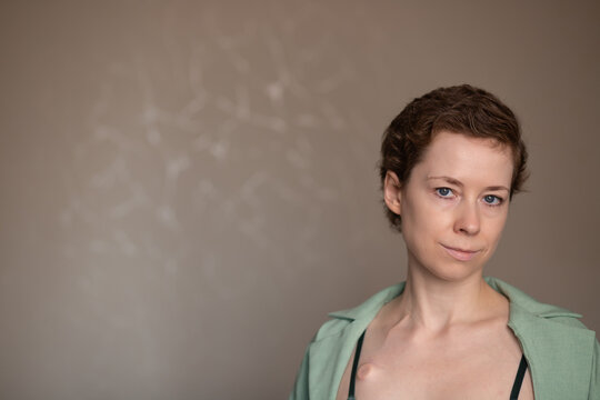 close portrait of a woman with an implanted port and slight smile, representing body confidence, patient resilience and authentic life during oncology recovery