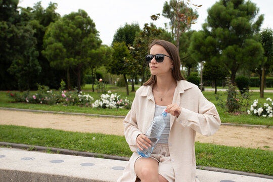teenager opens a water bottle while resting on a park bench, promoting hydration breaks and practical heat safety during summer outdoor activities for an active youth lifestyle