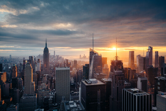 New York City Manhattan skyline in golden evening light against dramatic cloudscape at sunset, New York, USA