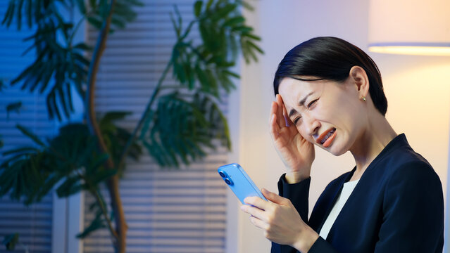 スマホを見ながら落ち込むミドル女性。失敗、困る、トラブル、アプリ、SNS、炎上、動画、後悔、投資