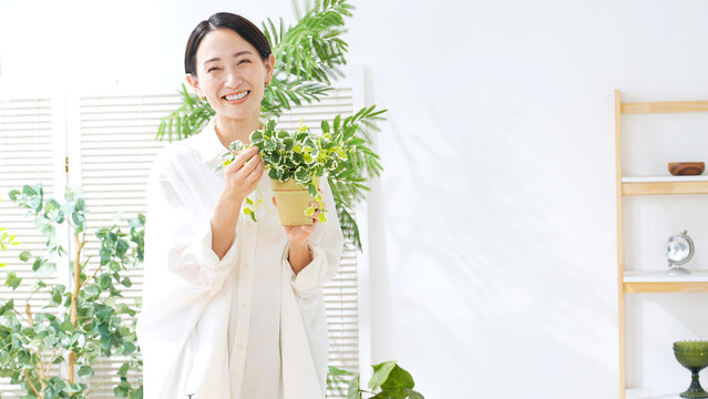 植物を持つミドル女性。ガーデニング、園芸、観葉植物、趣味、お手入れ、インドア、インテリア、笑顔、栽培
