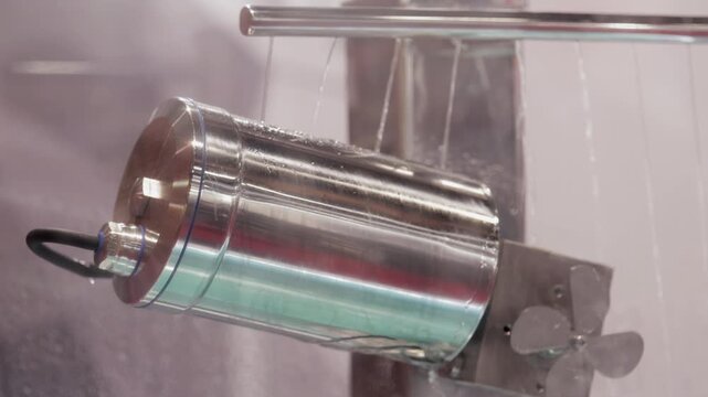 Experimental DC motor operates under water jets in lab chamber closeup. Powerful engine efficiently operates in wet enclosure shown at industrial exhibition